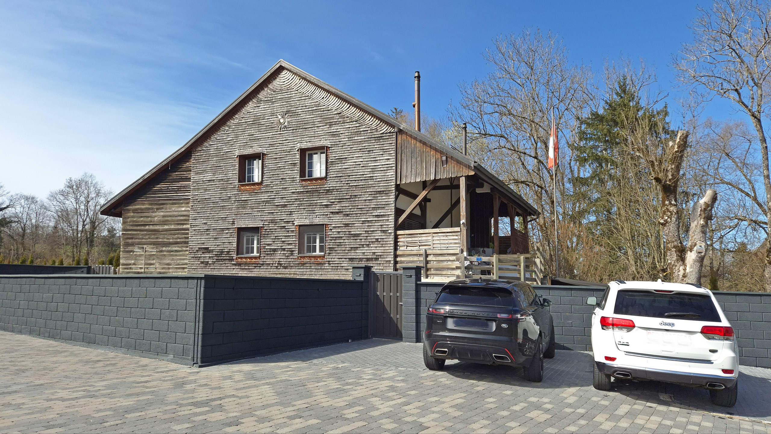 Holzhaus mit Schindelfassade und Einfahrt