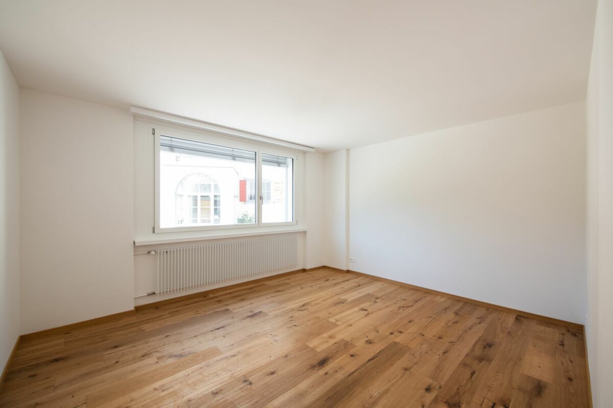 Heller leerer Wohnraum mit Parkettboden und Fenster