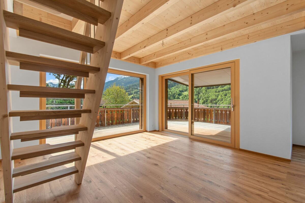 Heller Wohnraum mit Holztreppe und Bergblick
