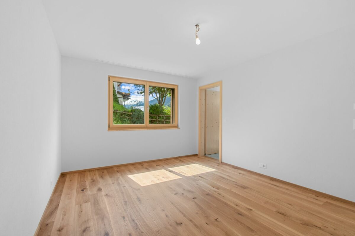 Heller leerer Raum mit Holzfußboden und Fensterblick