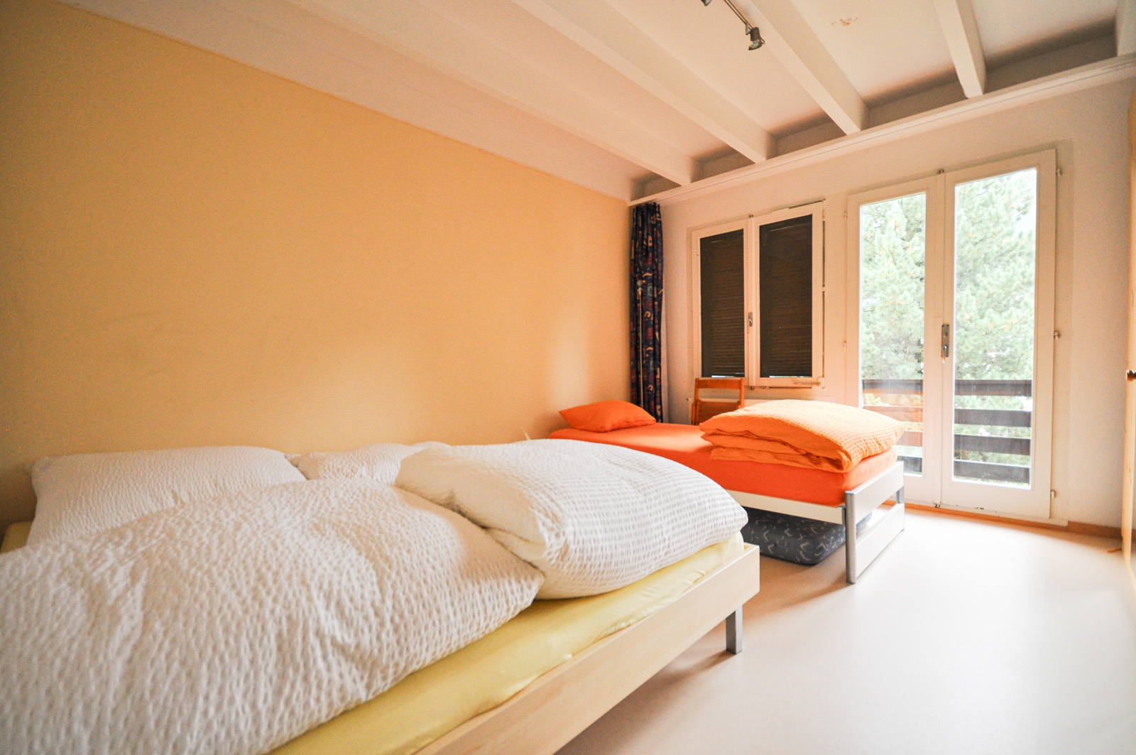 Helles Schlafzimmer mit zwei Betten und Balkonzugang