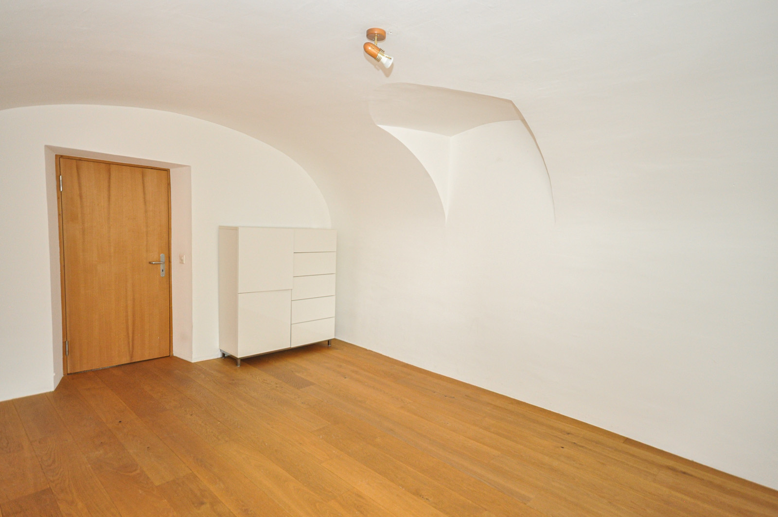 Leerer Raum mit Holztür und Sideboard