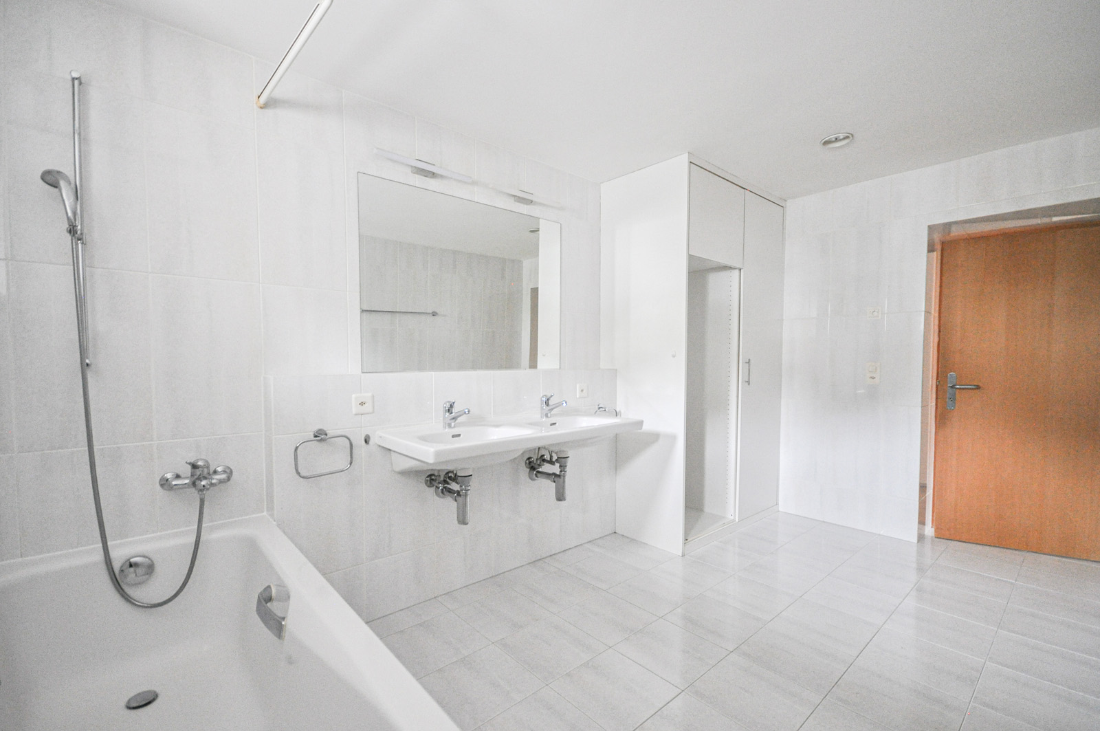 Helles Badezimmer mit Badewanne, Doppelwaschtisch und Einbauschrank