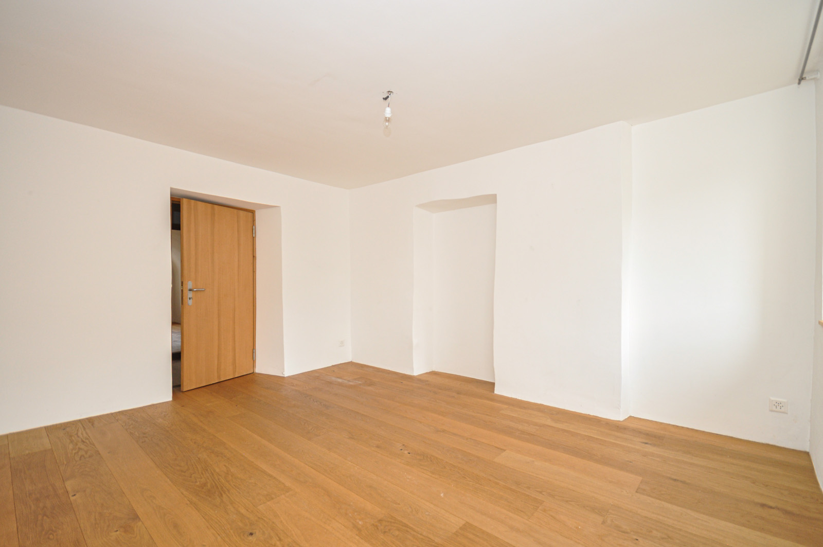 Leeres Zimmer mit Holzboden und offener Tür