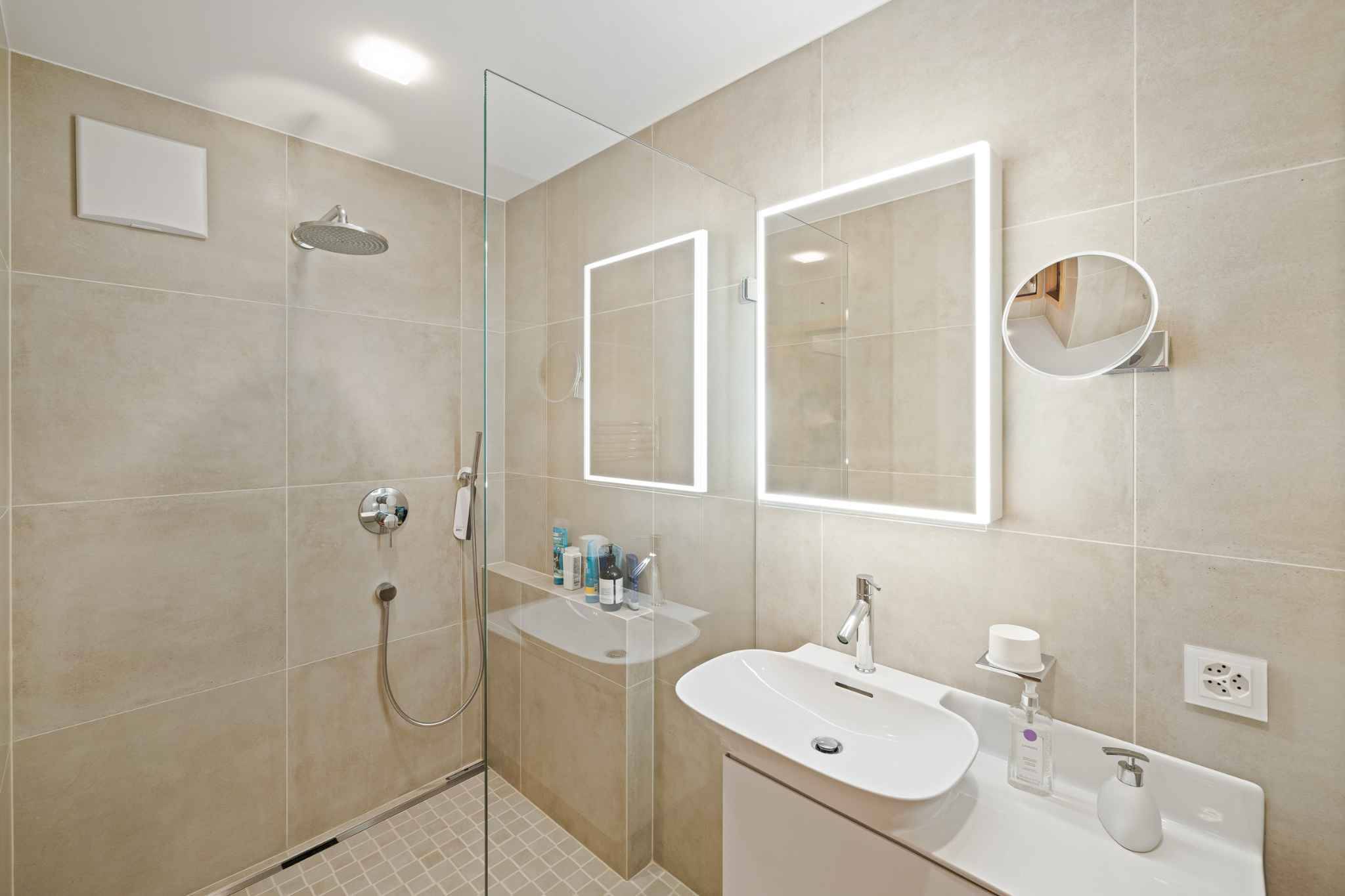 Modernes Badezimmer mit begehbarer Dusche und beleuchtetem Spiegel