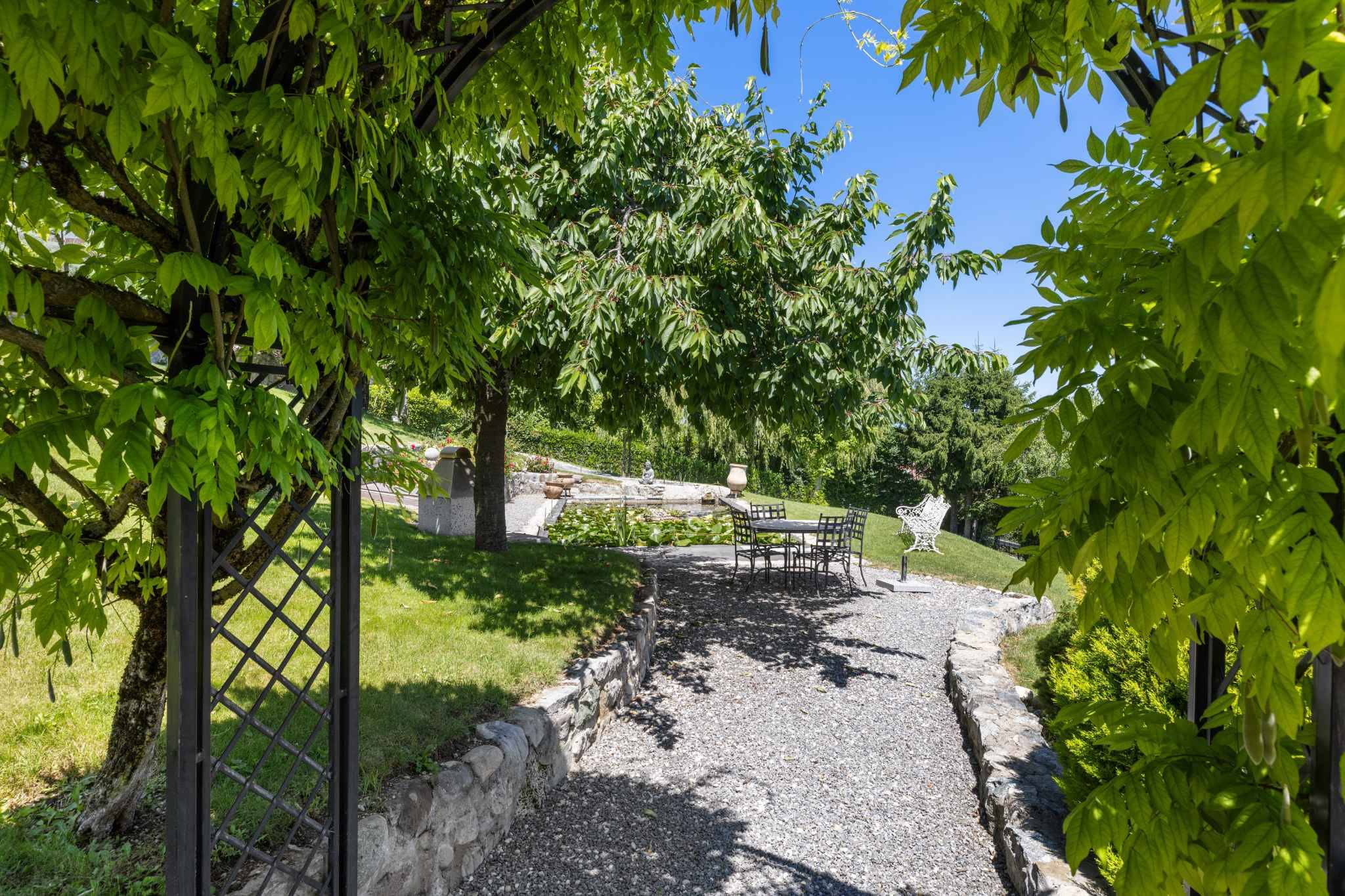 Gartenweg mit Sitzplatz unter grünem Laubdach