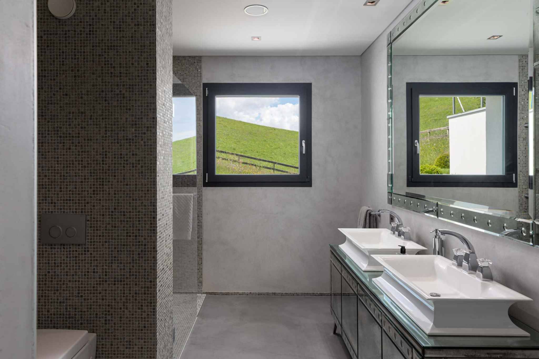 Modernes Badezimmer mit Doppelwaschbecken und Blick ins Grüne