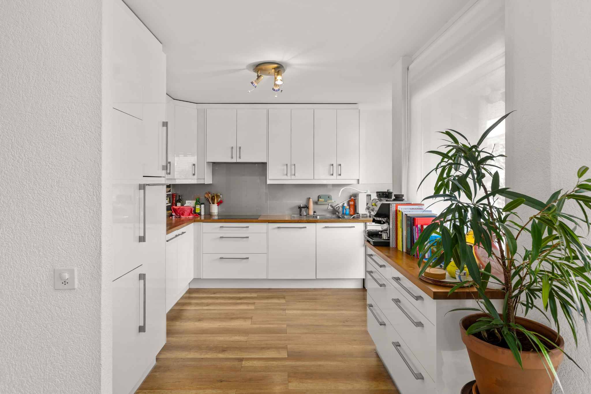 Moderne weiße Küche mit Holzarbeitsplatte