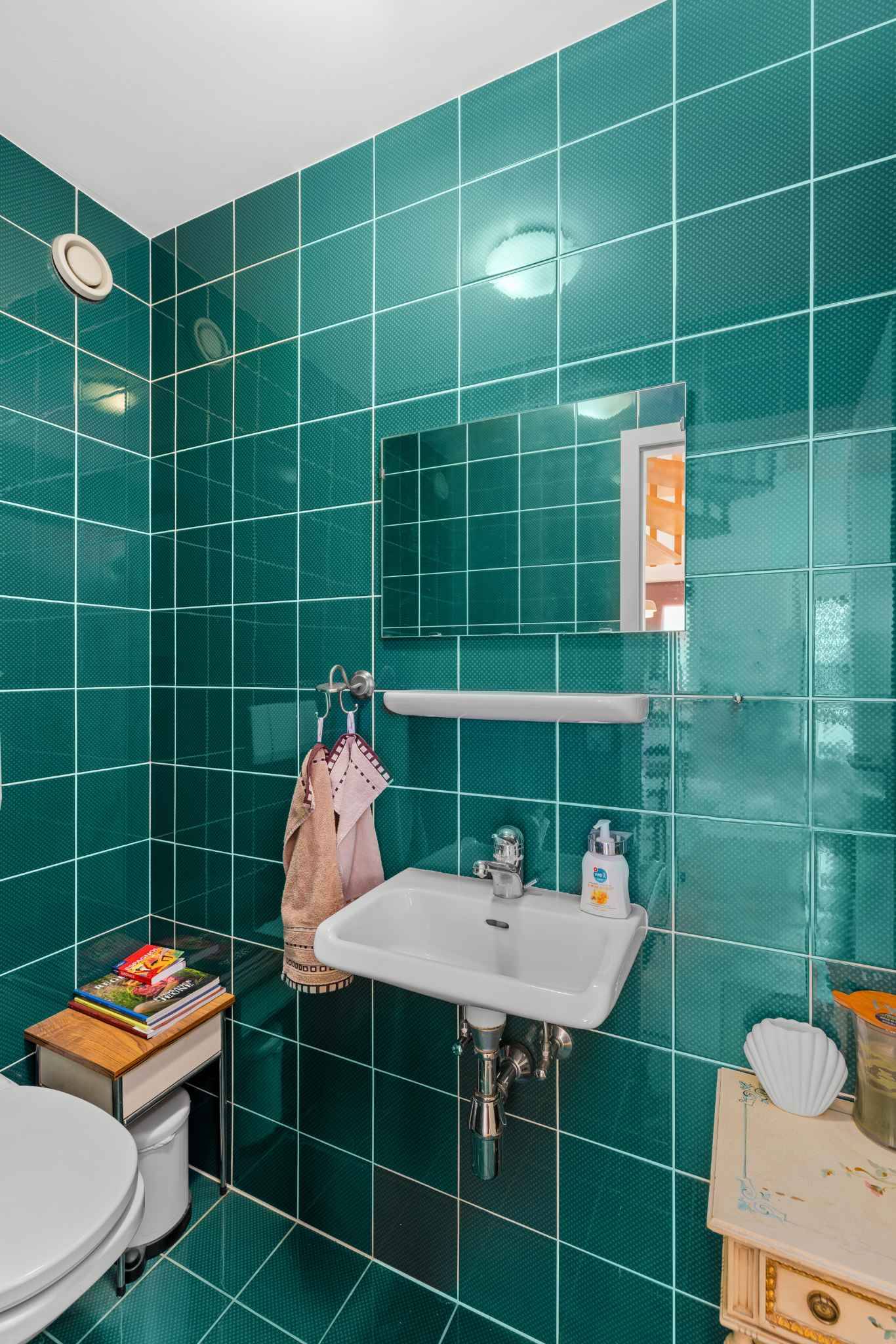 Kleines Gäste-WC mit türkisfarbenen Wandfliesen und Wandwaschbecken