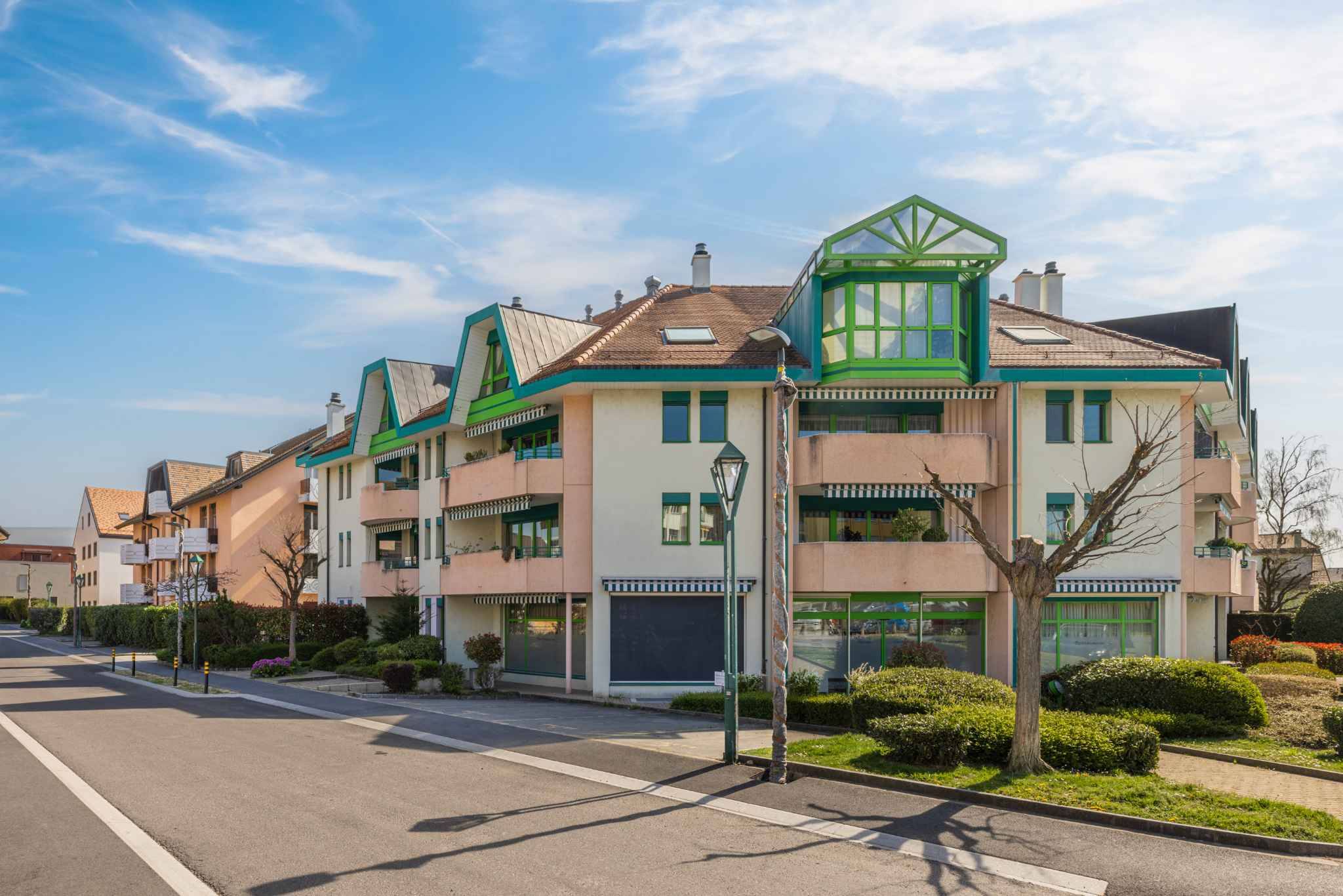 Mehrfamilienhaus mit auffälligen grünen Dach- und Fensterdetails