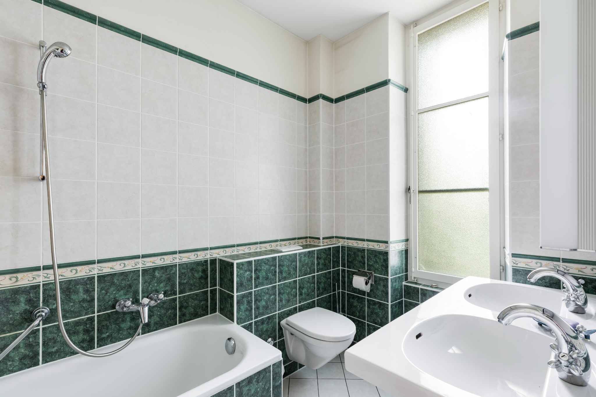 Badezimmer mit grün-weißer Fliesenverkleidung
