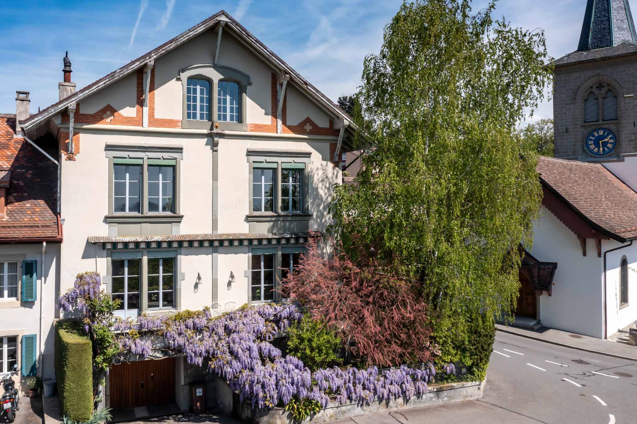 Historisches Wohnhaus mit Garten und Kirchturm im Hintergrund