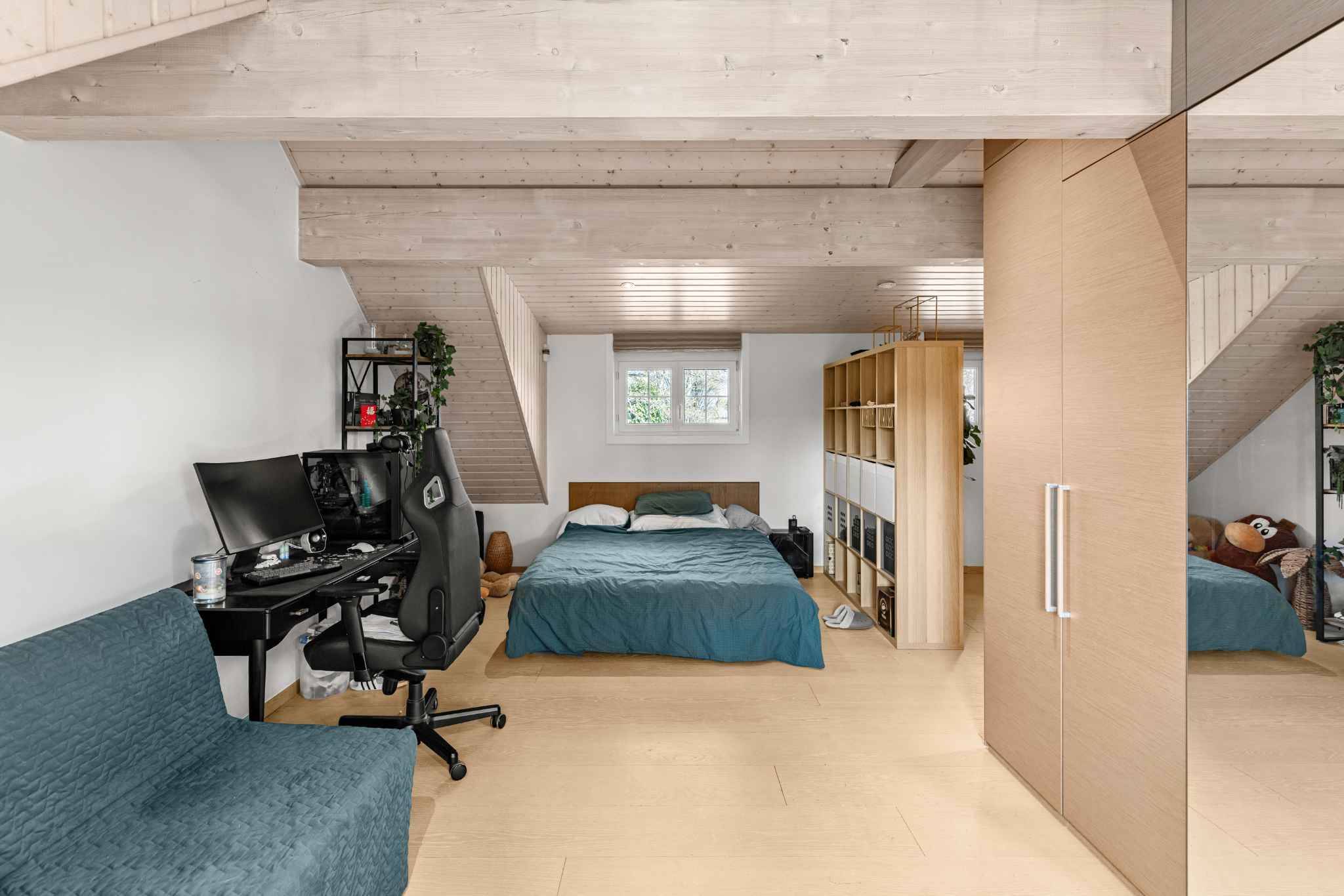 Mansardenzimmer mit Bett und Arbeitsbereich
