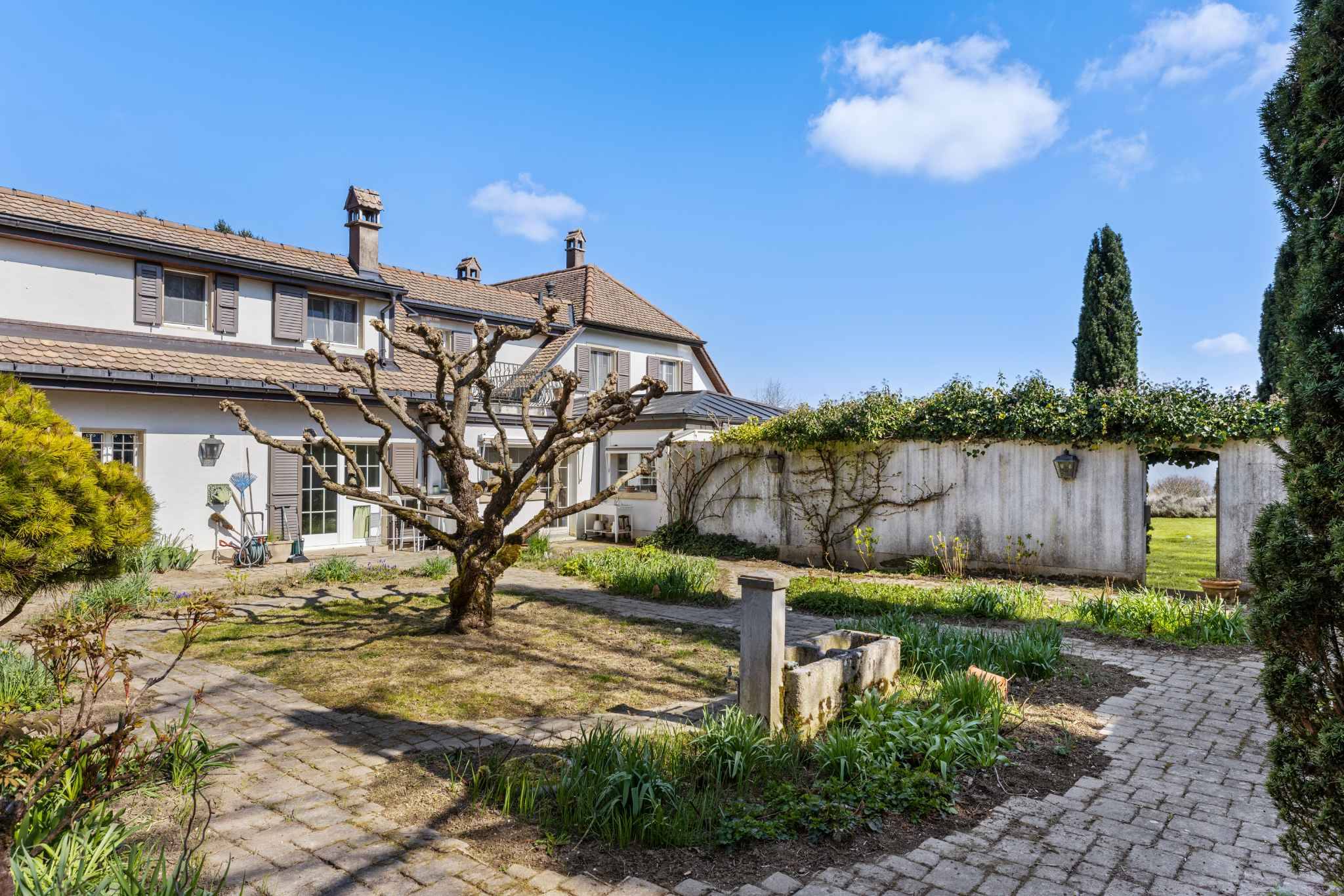 Großer mediterran wirkender Garten mit klassischem Wohnhaus