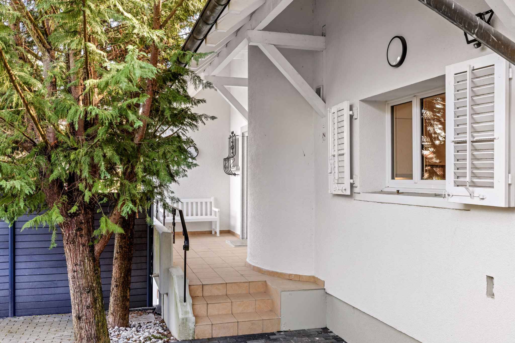 Weiße Hausfassade mit Fensterläden und Außentreppe