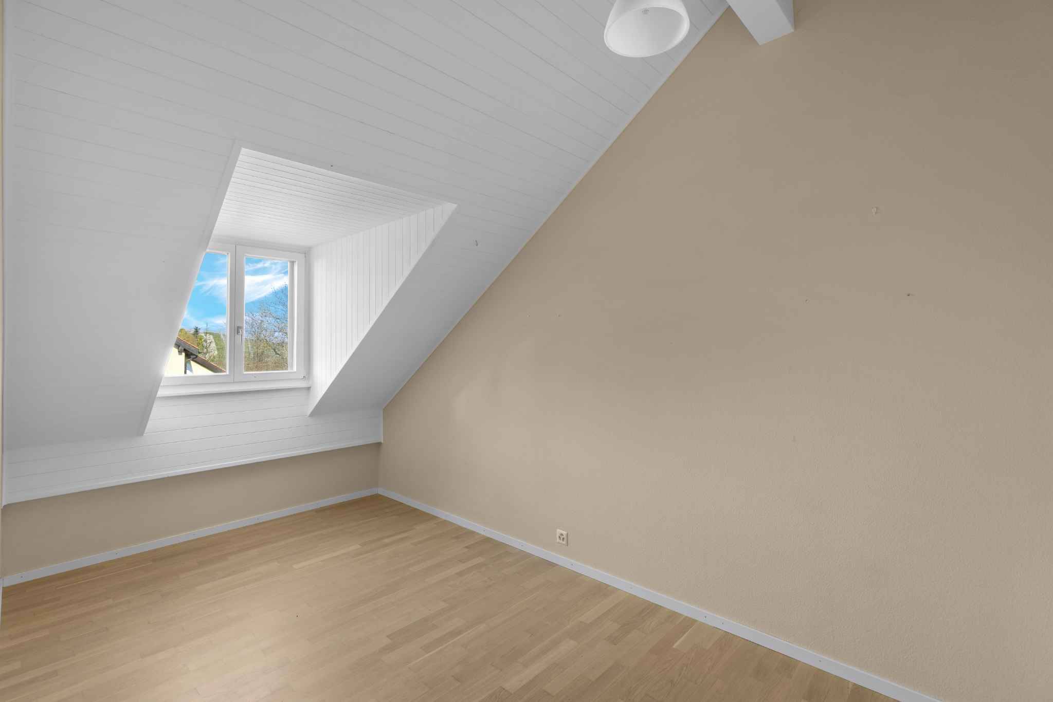 Dachgeschosszimmer mit Schrägen und Fenster