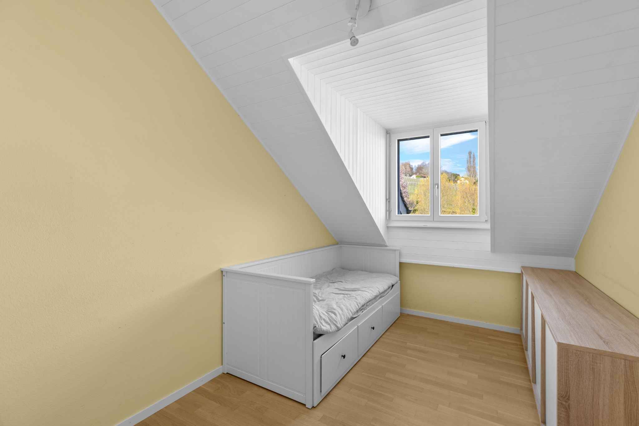 Dachgeschosszimmer mit Bett und Fenster