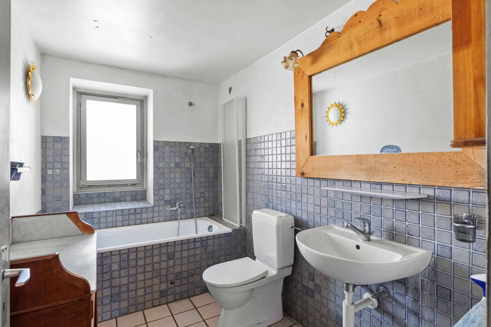 Badezimmer mit Badewanne und Holzspiegel