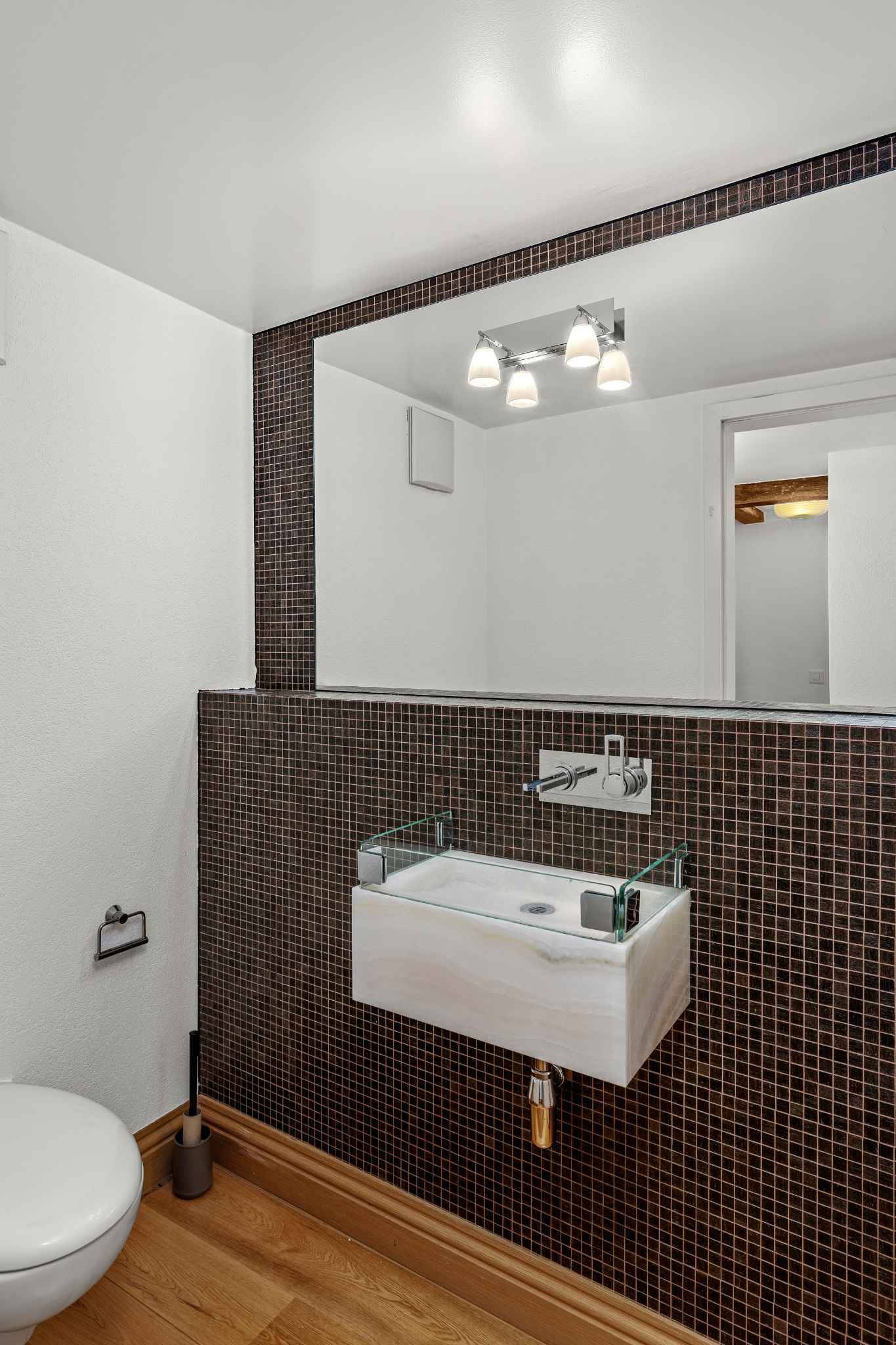 Modernes Gäste-WC mit dunkler Mosaikwand und schwebendem Waschtisch