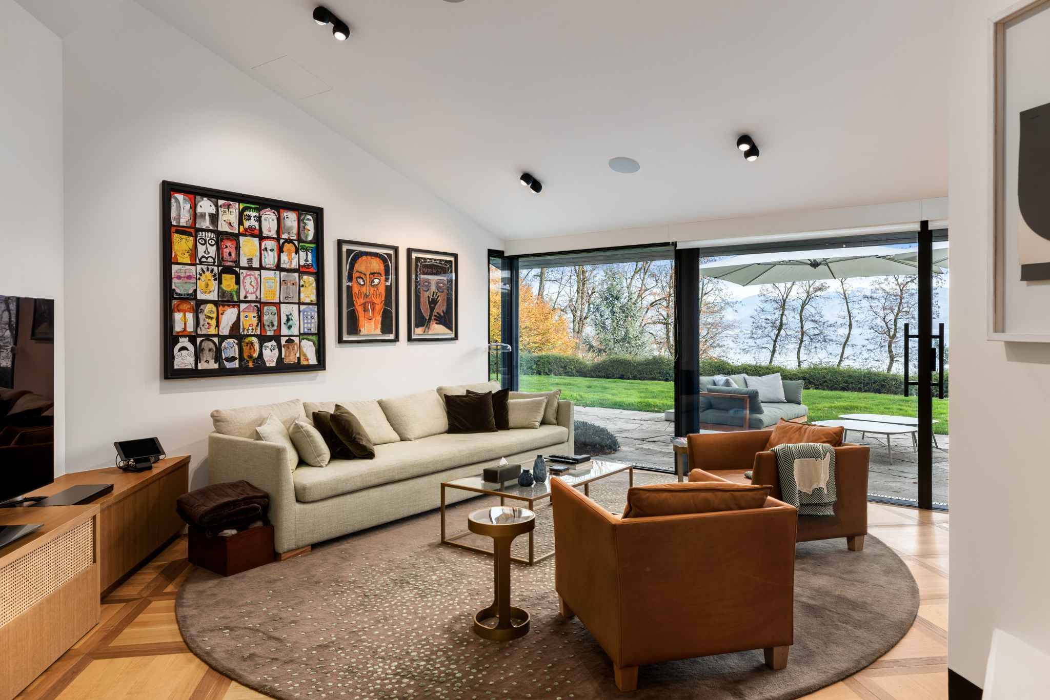 Wohnzimmer mit großflächiger Glasfront und Seeblick