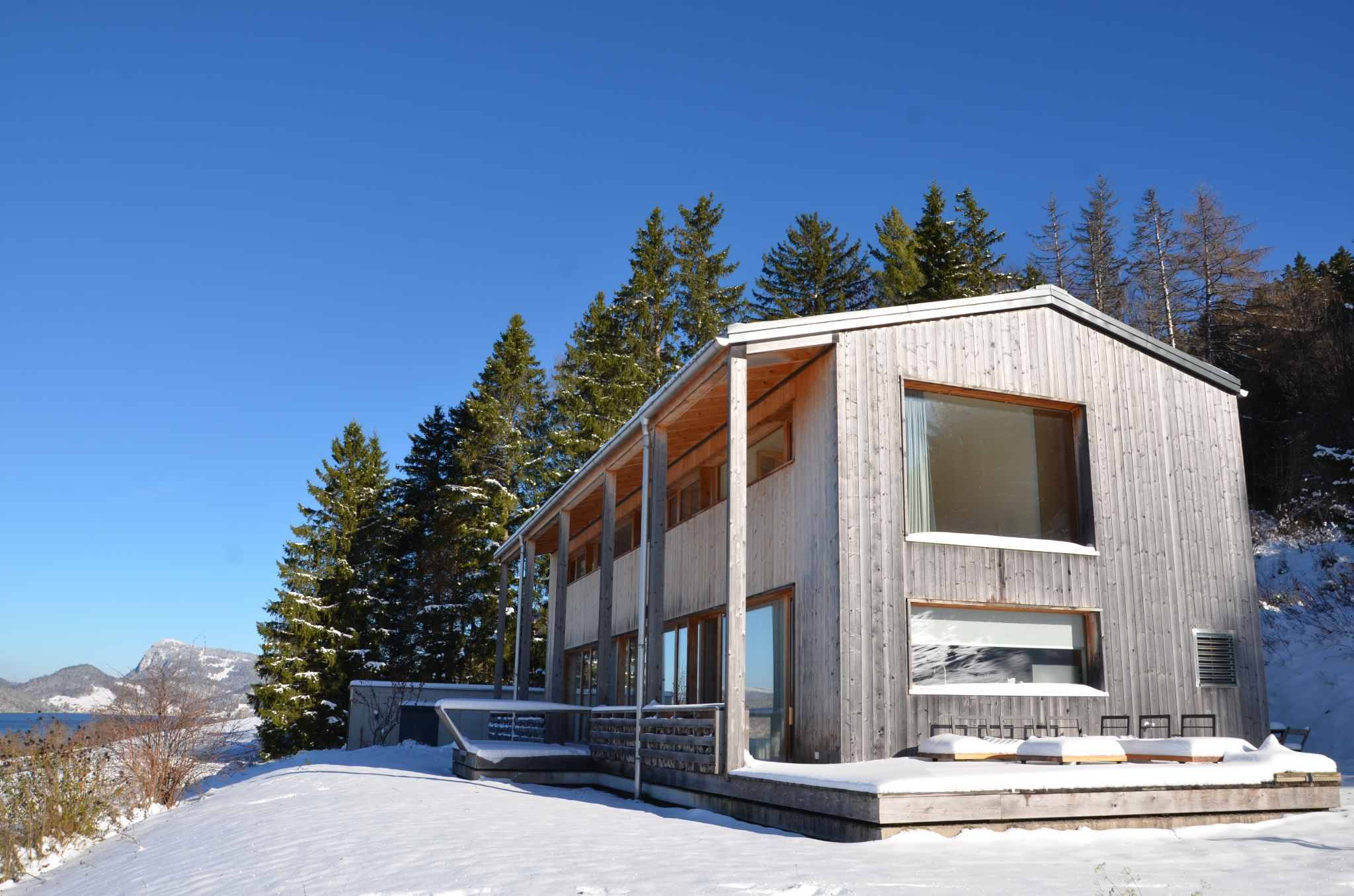 Modernes Holzhaus im Schnee mit Bergblick