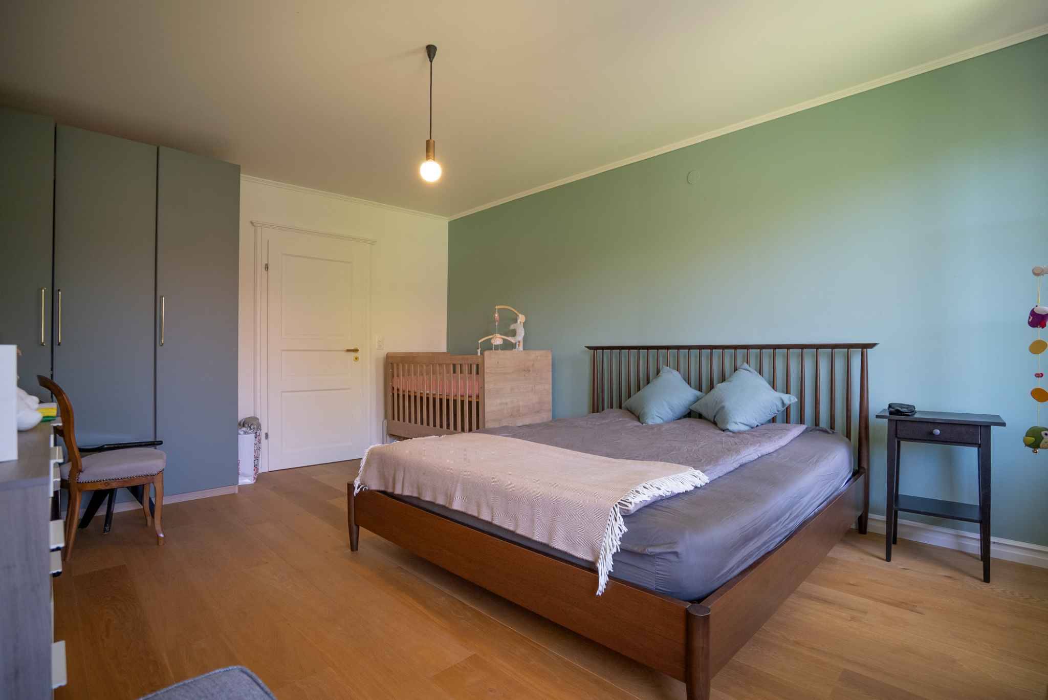 Schlafzimmer mit Naturholzmöbeln und pastellgrüner Akzentwand
