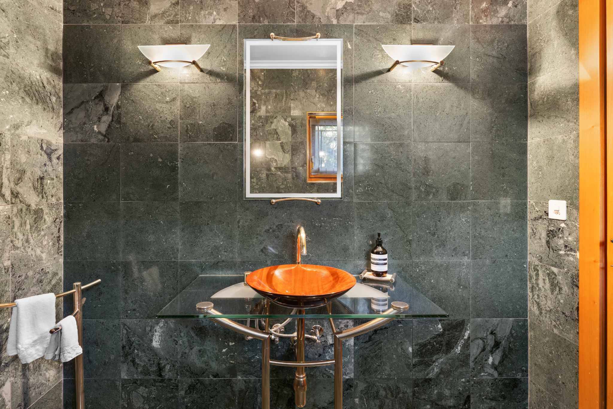 Luxuriöses Badezimmer mit Naturstein und Glaswaschtisch