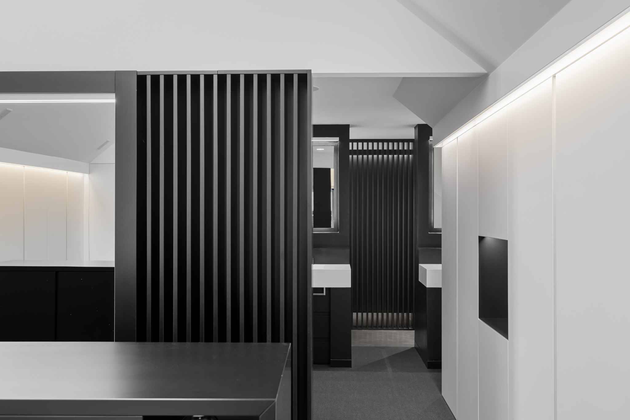 Moderne Ankleide oder Badezimmerzone mit dunklen Lamellen und weißen Einbauten