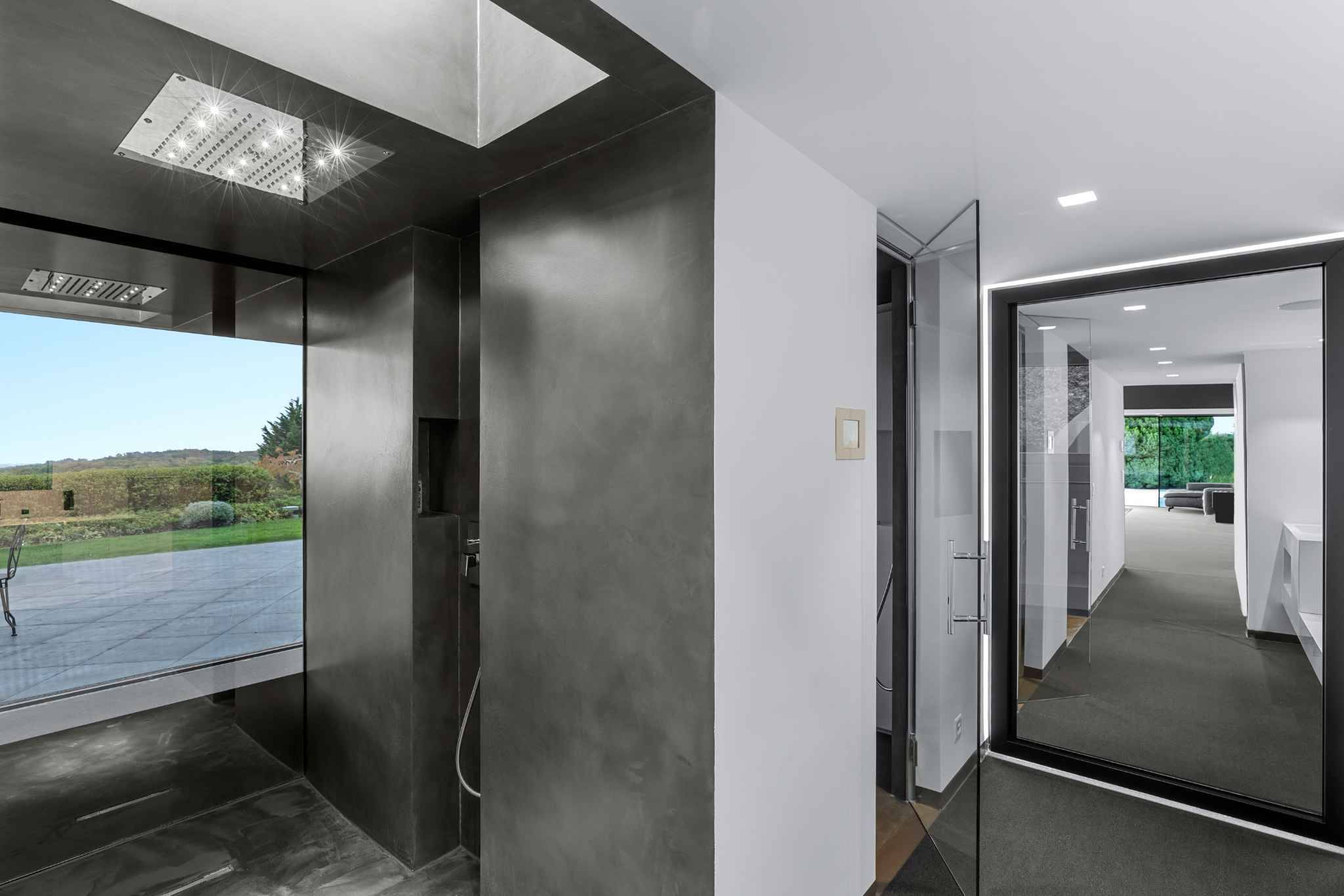 Moderne Innenansicht mit großformatigen Glasflächen und dunkler Nasszone