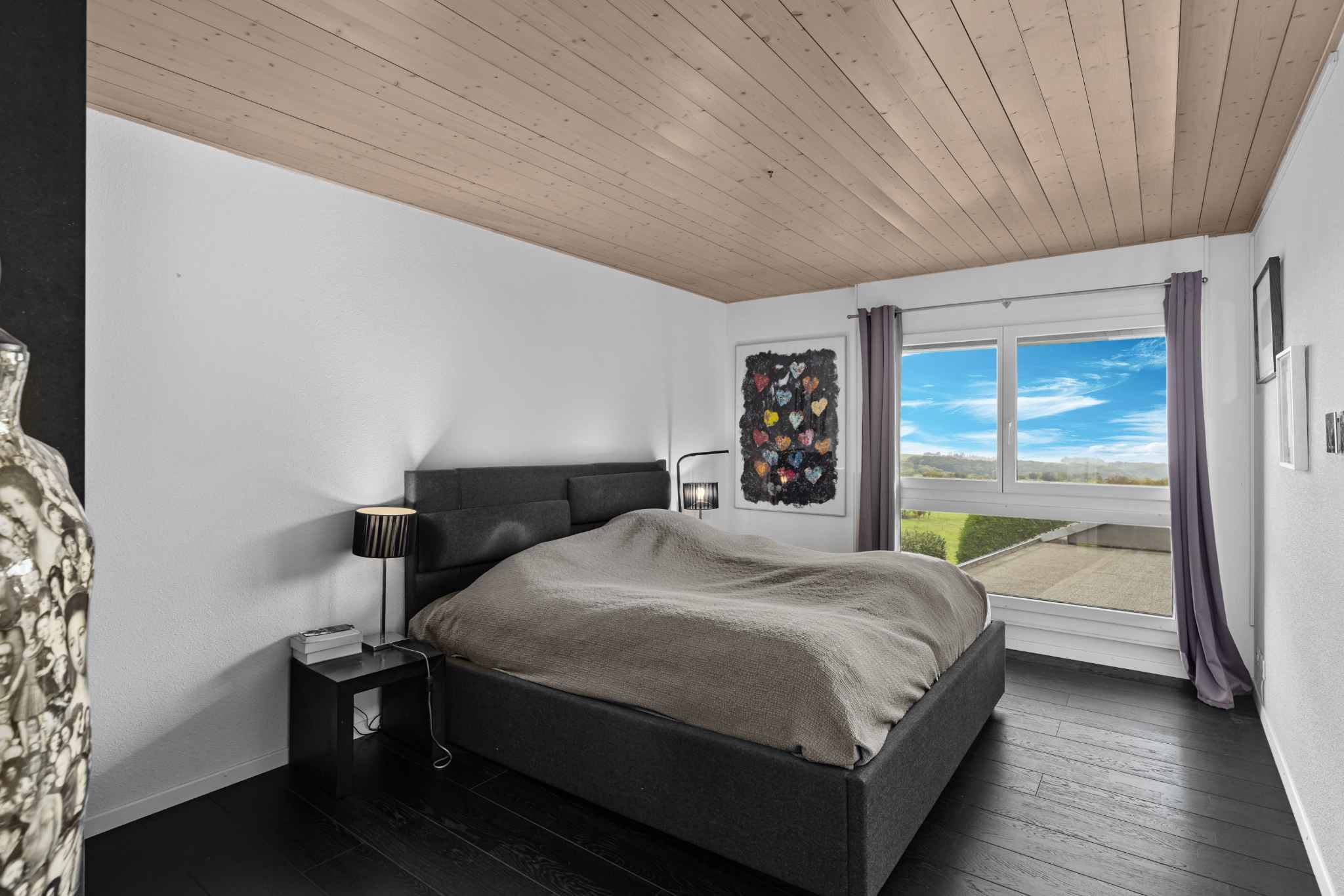 Schlafzimmer mit dunklem Boden und großem Fenster