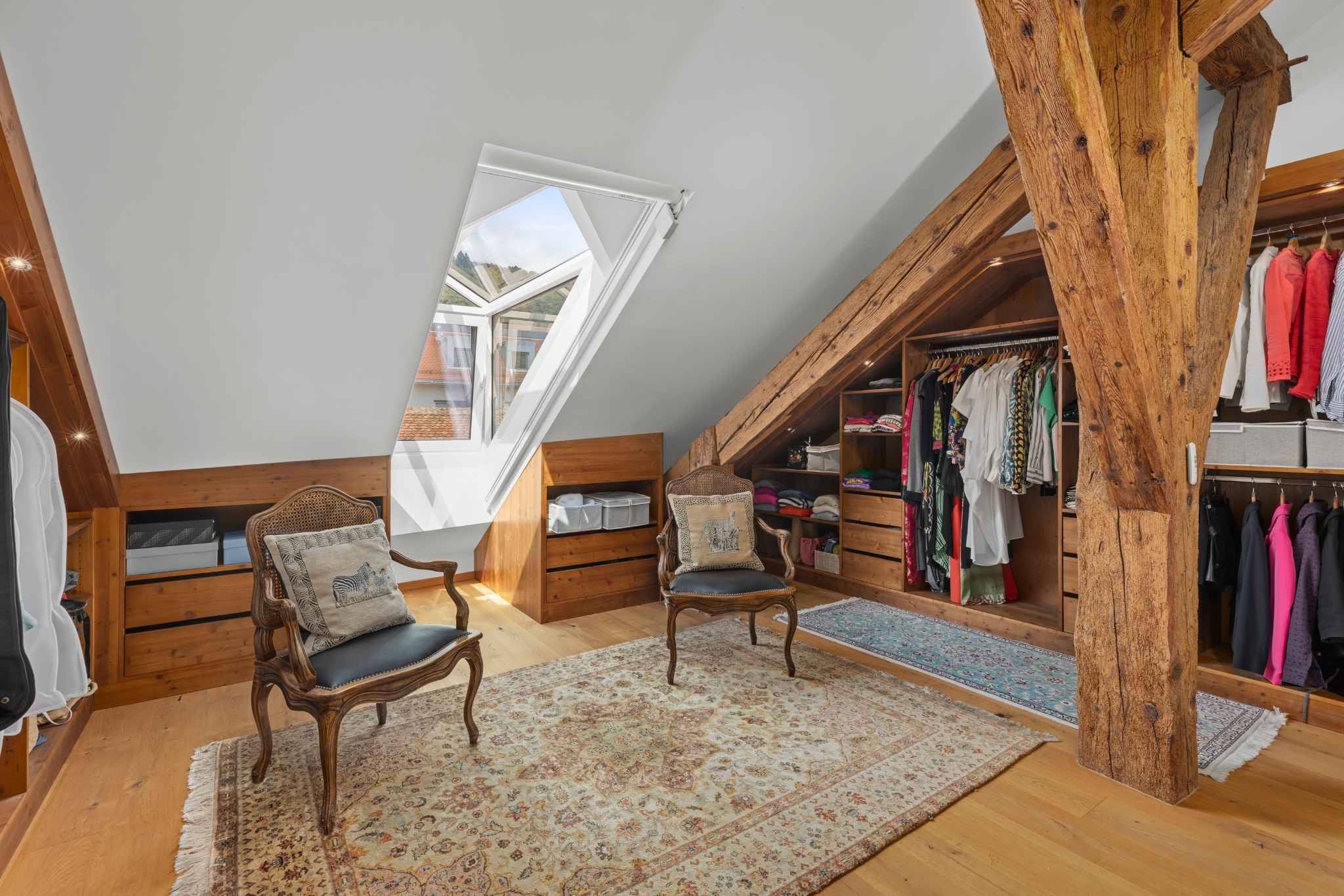 Dachgeschoss-Ankleidezimmer mit sichtbaren Holzbalken