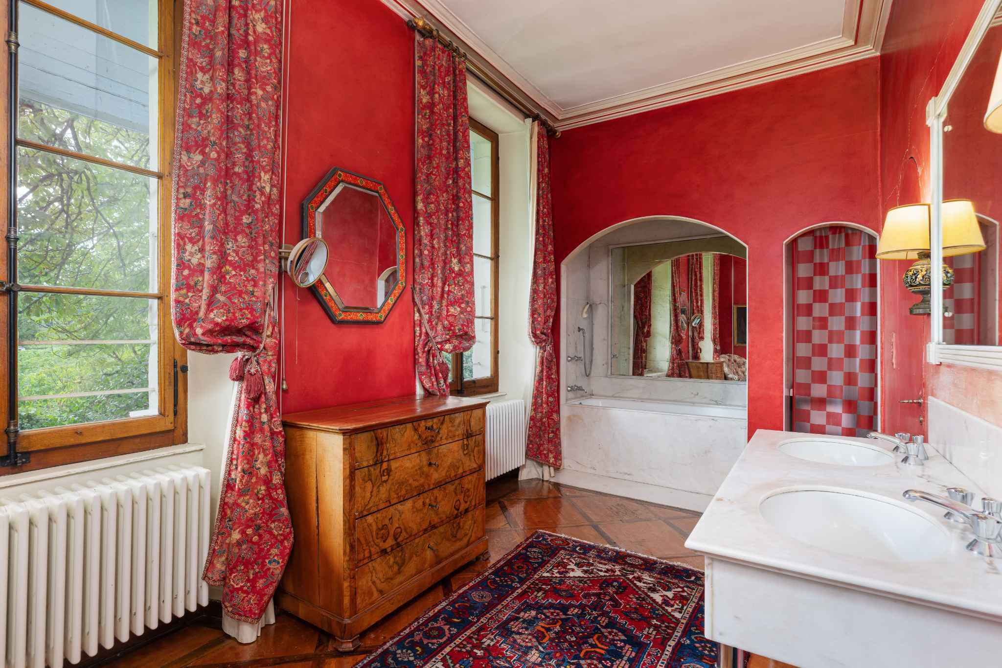 Opulentes Badezimmer mit roter Wandfarbe und floralen Vorhängen