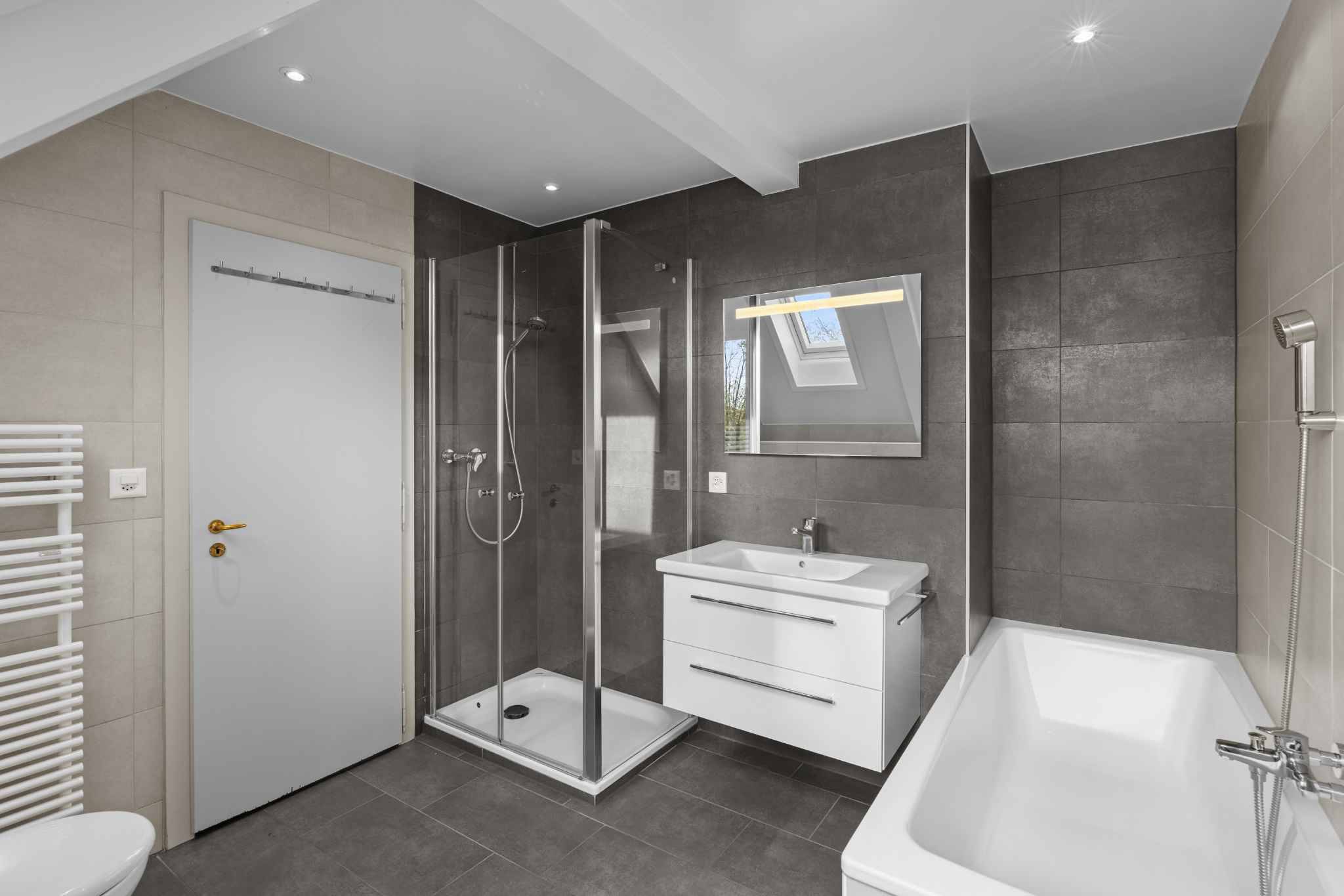 Modernes Badezimmer mit Dusche, Wanne und Dachfenster