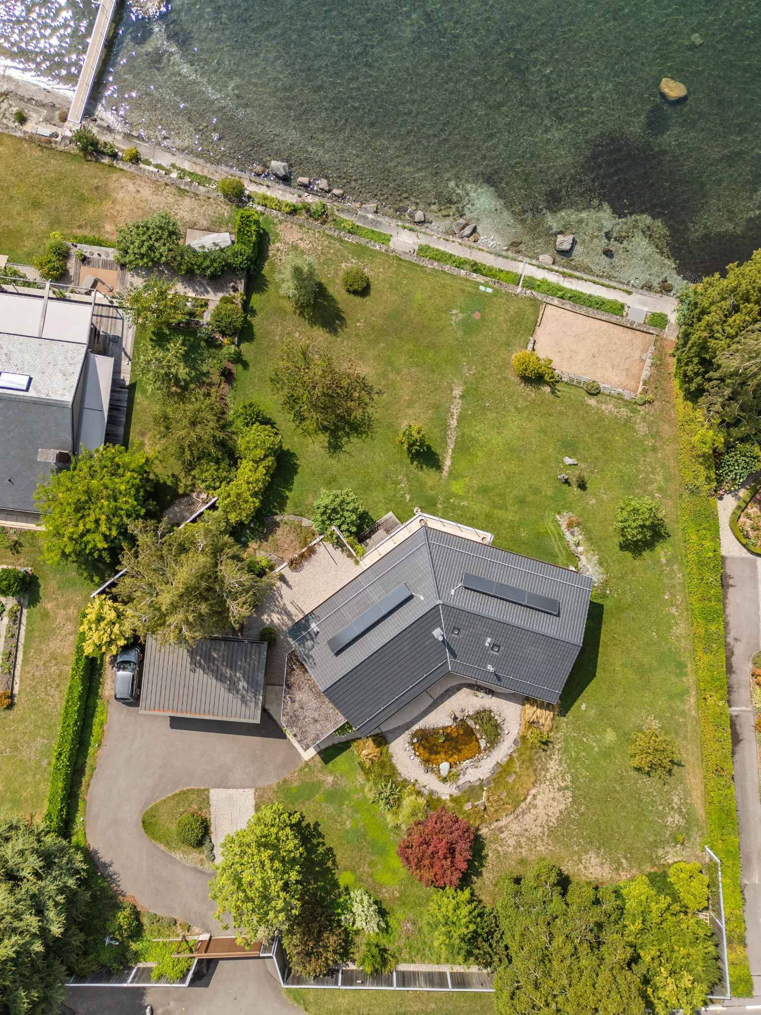 Luftaufnahme eines Seegrundstücks mit Wohnhaus und Garten