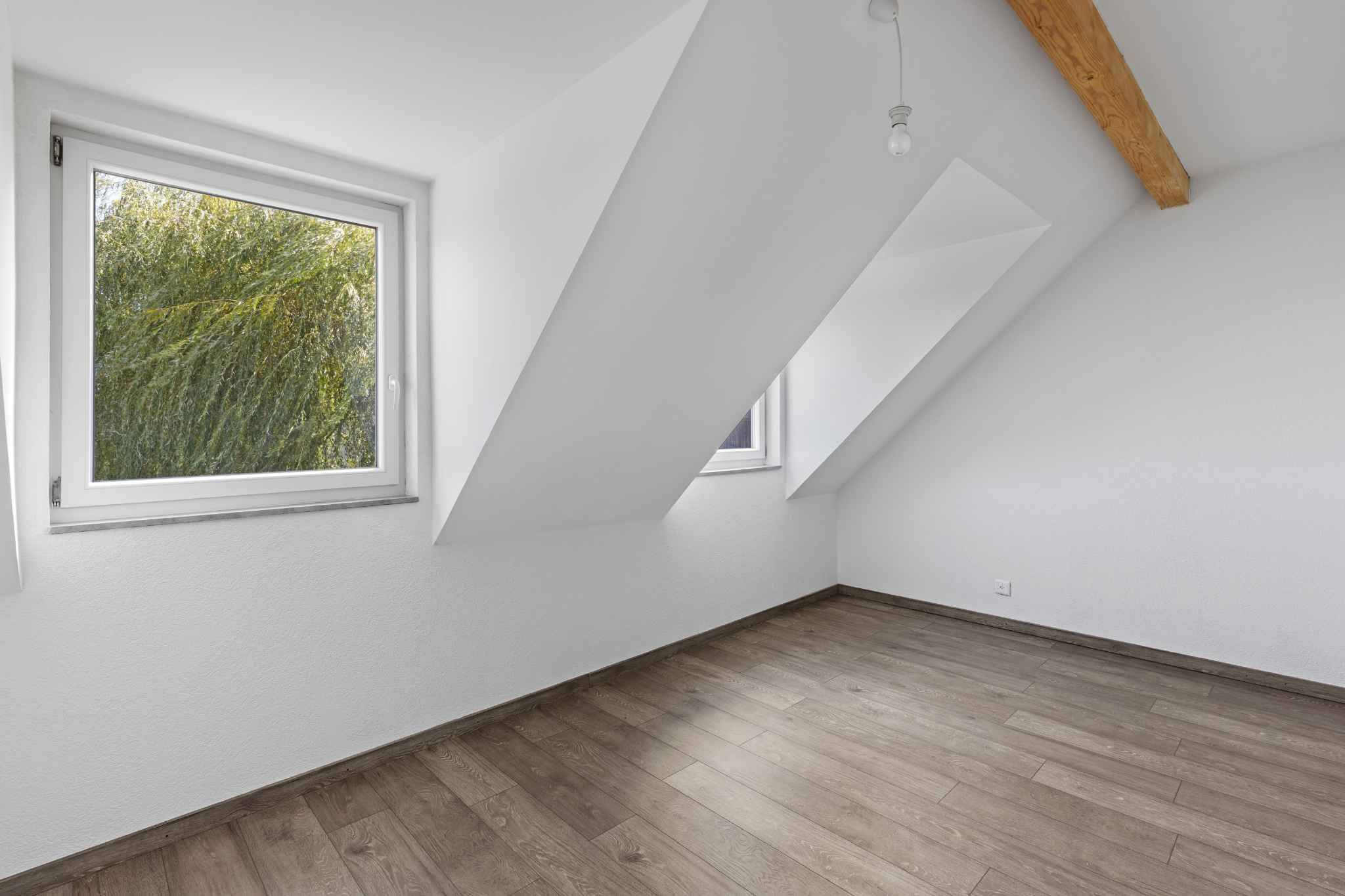 Dachzimmer mit zwei Fenstern und Holzdecke