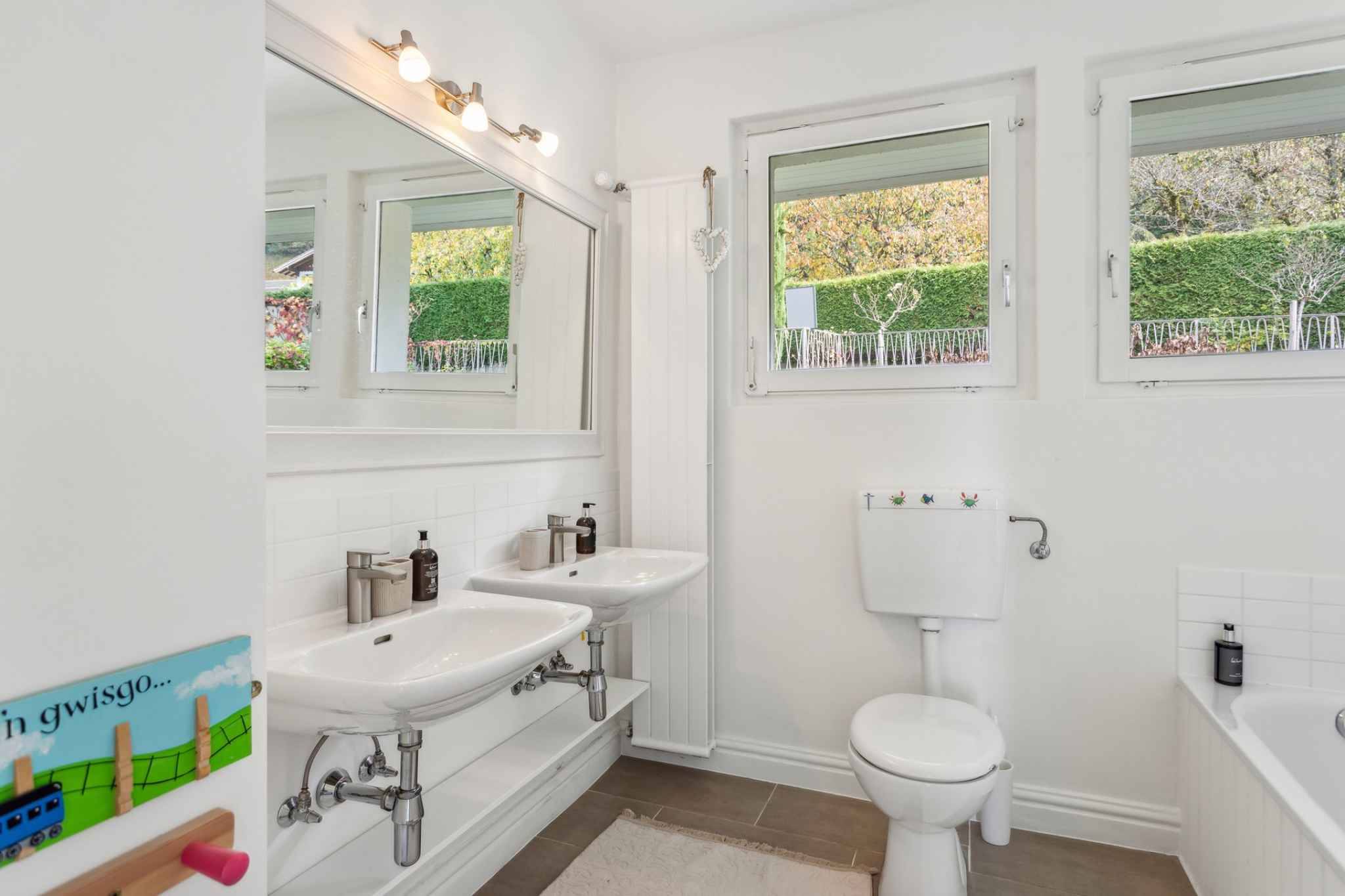 Helles Gäste-WC mit zwei Waschbecken und Fensterblick