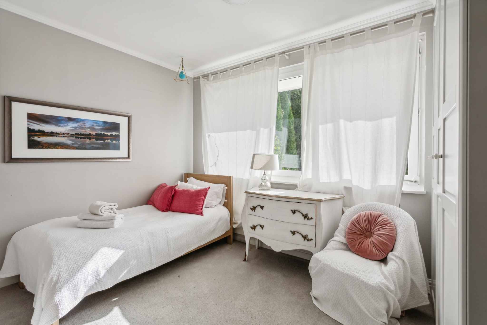 Helles Schlafzimmer mit Einzelbett und Fensterfront