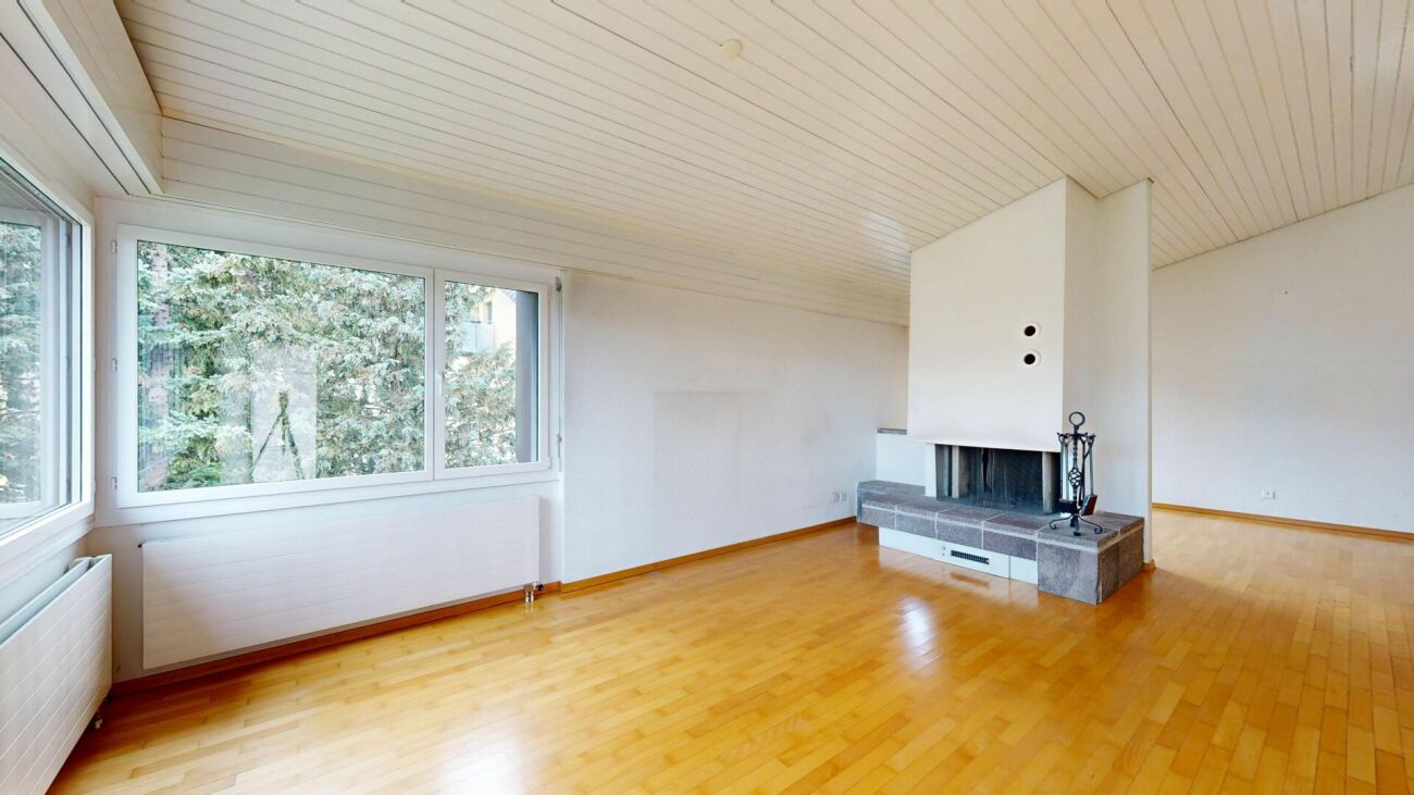 Wohnzimmer mit Kamin und großen Fenstern