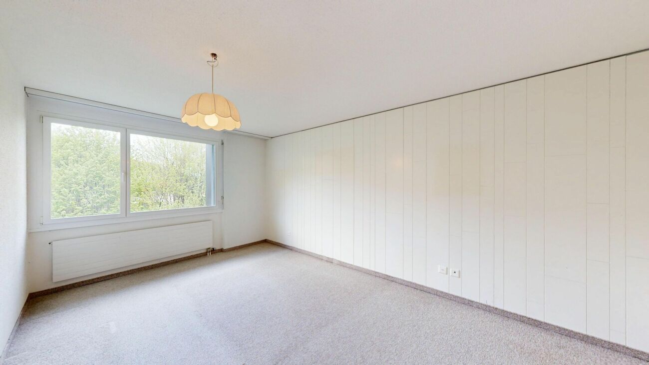 Helles, leeres Schlafzimmer mit Fenster und Heizkörper