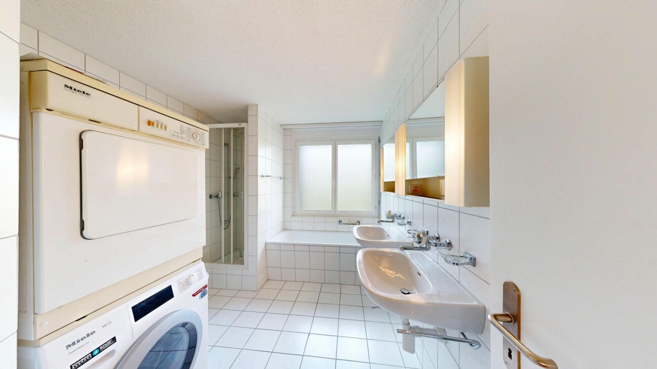 Badezimmer mit Waschmaschine und Doppelwaschbecken