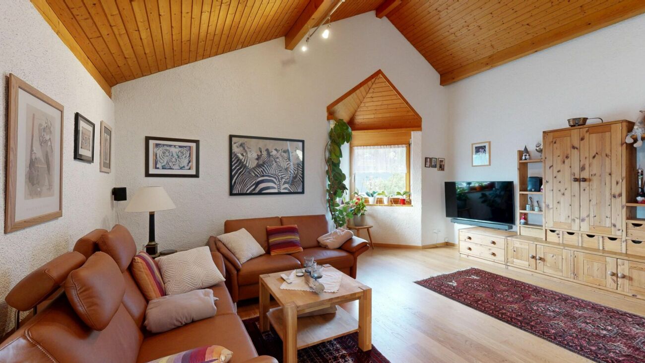 Gemütliches Wohnzimmer mit Holzdecke und warmen Holzmöbeln