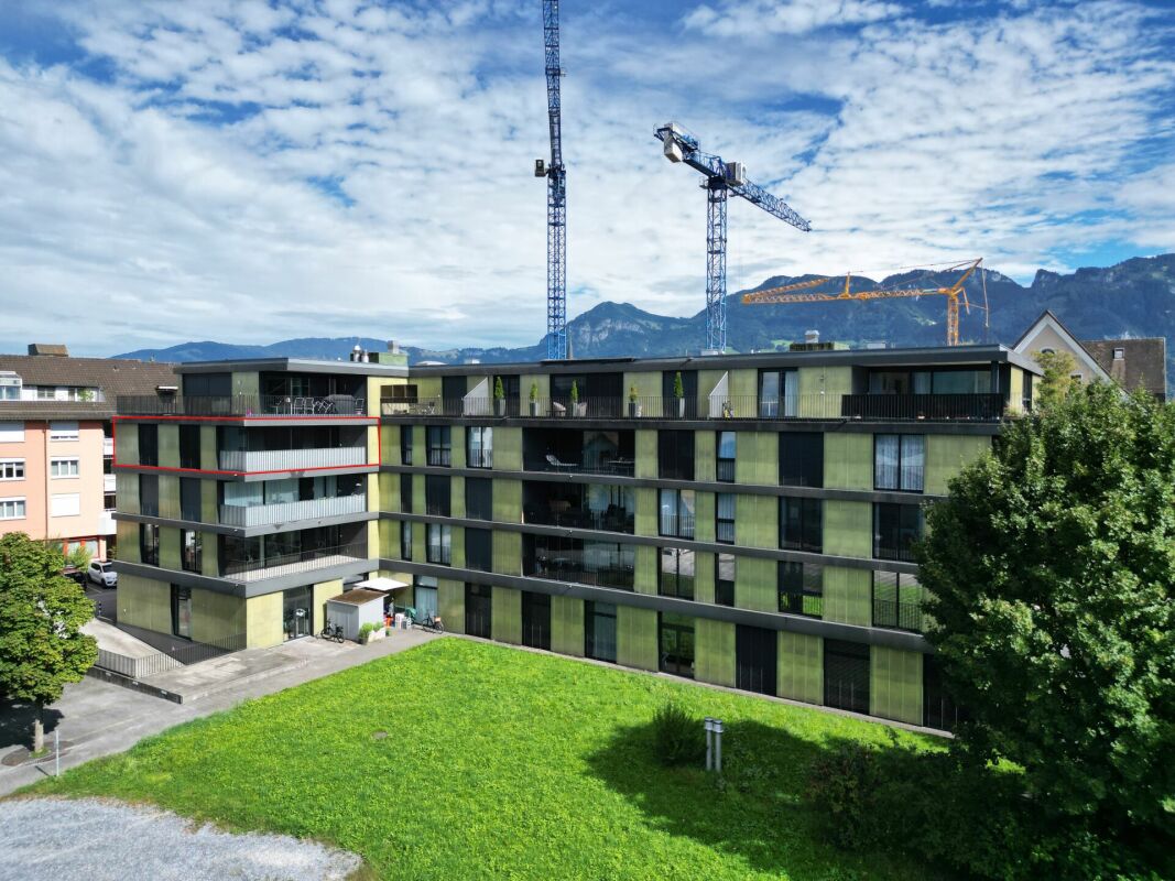 Moderne Wohnanlage mit Grünfläche und Bergkulisse