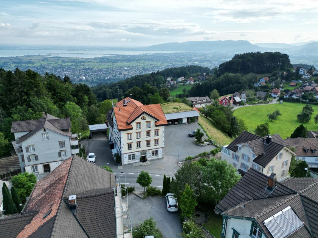 Blick über eine Wohnlage am Hang mit See- und Bergpanorama