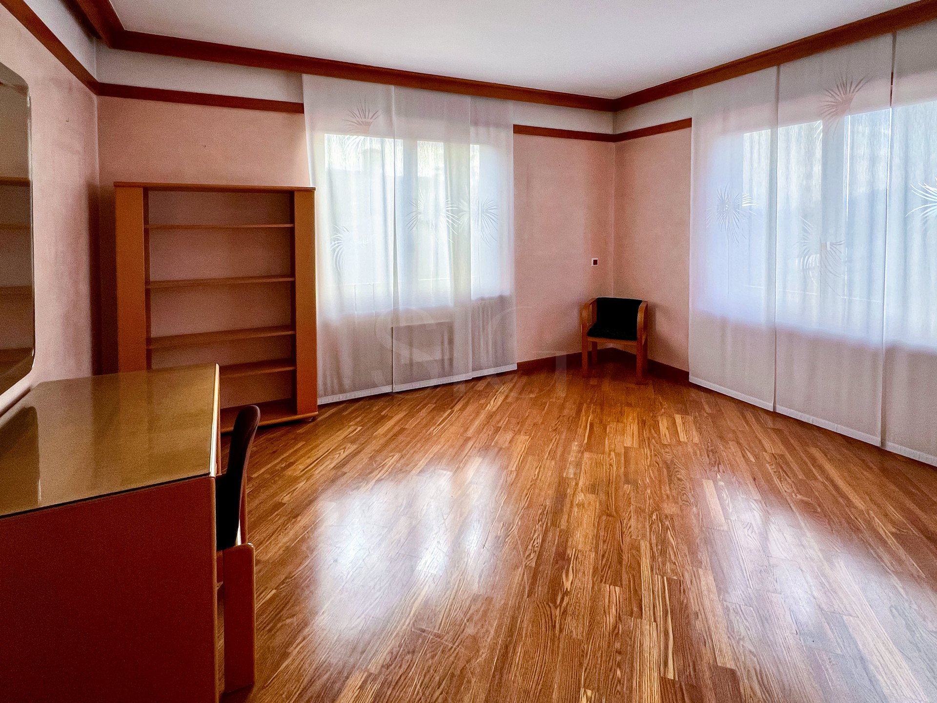 Helles, leeres Zimmer mit Holzoptik-Boden