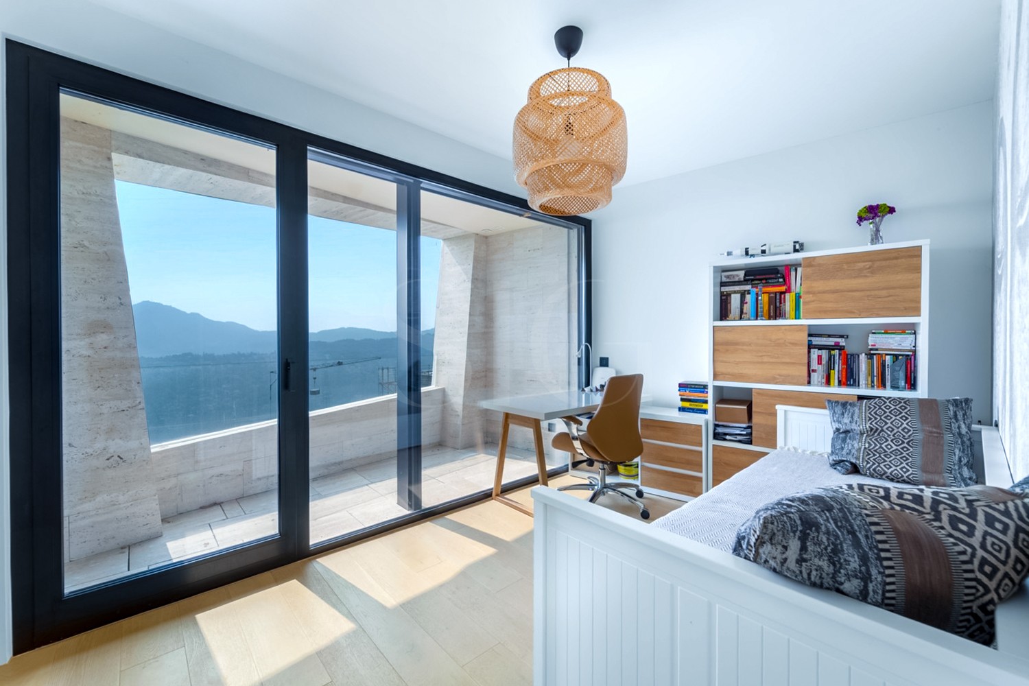 Helles Schlafzimmer mit Arbeitsplatz und Balkonblick