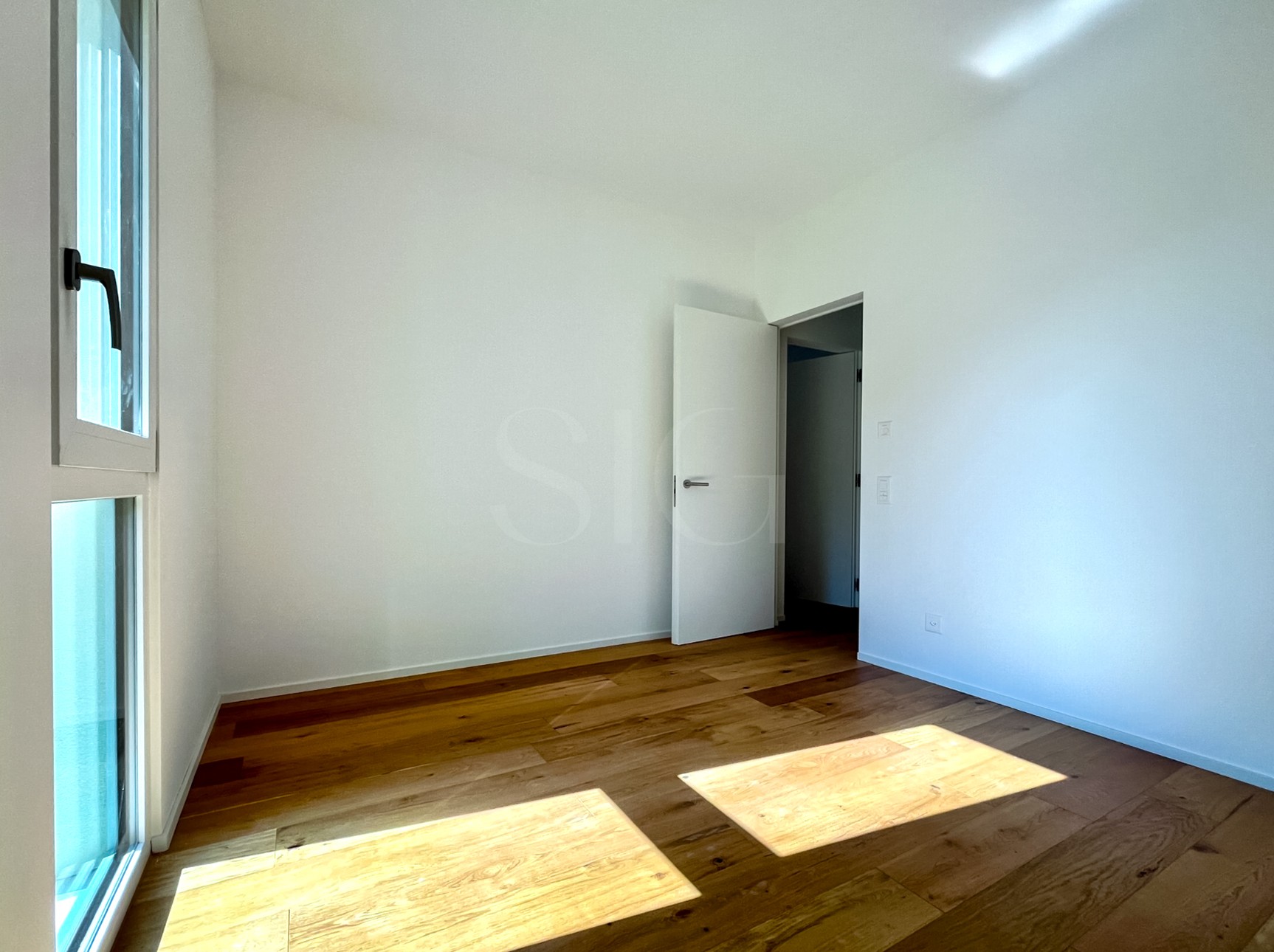 Heller leerer Raum mit Holzboden und Fensterelementen