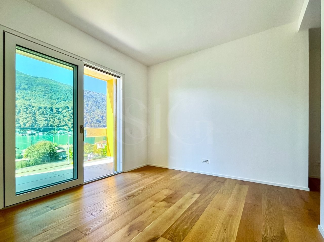 Helles leeres Zimmer mit Balkon- oder Terrassentür und Bergblick