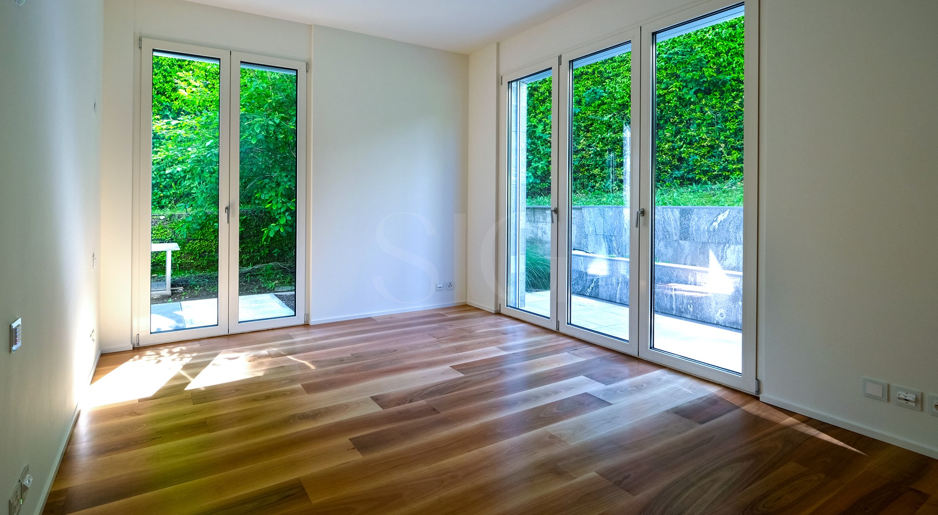 Heller Raum mit großen Glasfenstern zum Grün