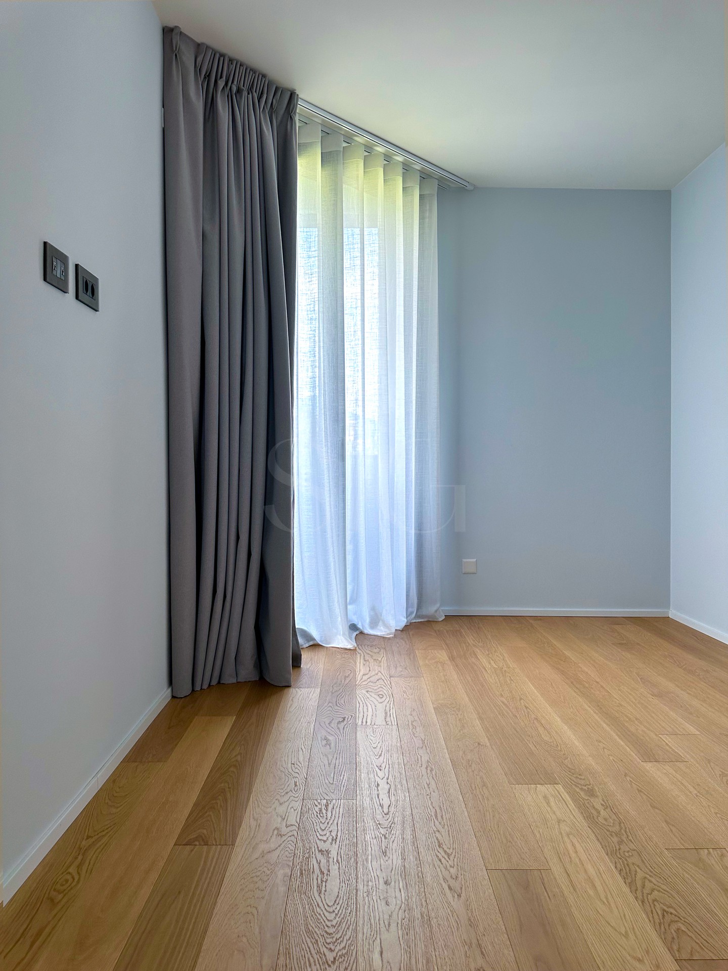 Heller leerer Raum mit Vorhängen und Holzfußboden