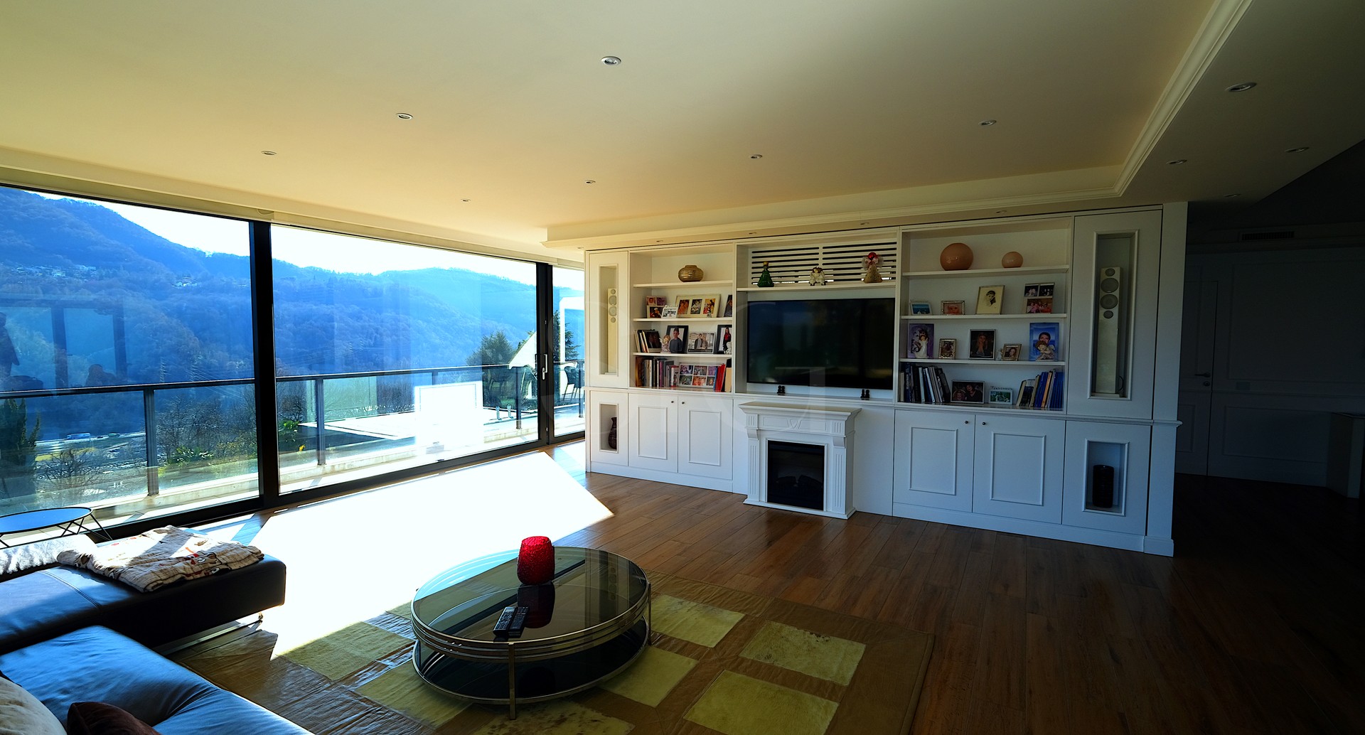 Helles Wohnzimmer mit Panoramafenster und Einbauschrankwand